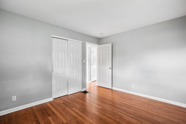 unfurnished bedroom with baseboards, wood finished floors, and a closet