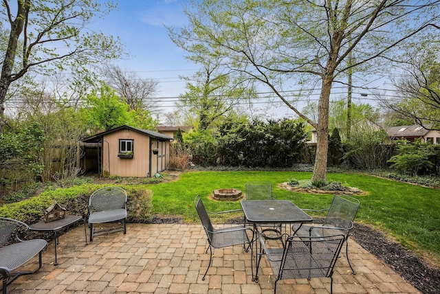 view of patio / terrace featuring a fenced backyard, a storage unit, an outbuilding, and an outdoor fire pit
