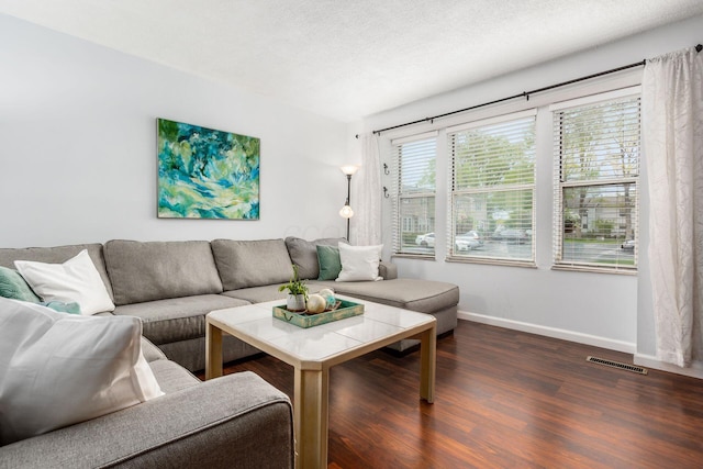 living area featuring visible vents, dark wood-style flooring, and baseboards