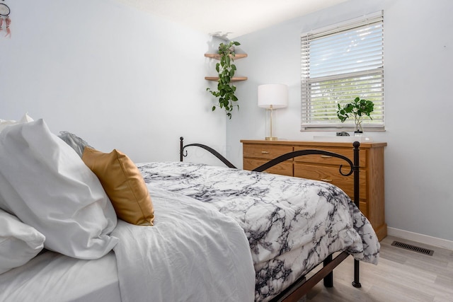 bedroom featuring visible vents, baseboards, and wood finished floors
