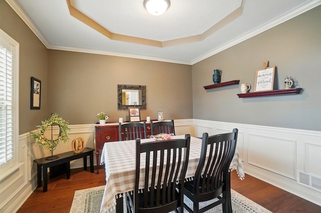 dining space with a raised ceiling, wood finished floors, and a wealth of natural light