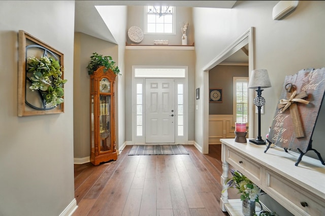 entrance foyer featuring wood-type flooring, baseboards, and a towering ceiling