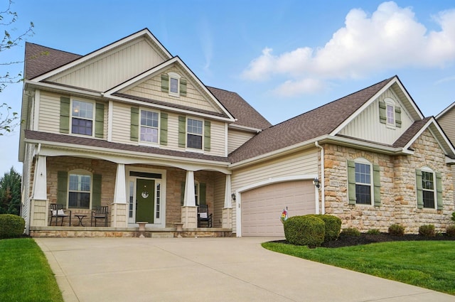 craftsman inspired home featuring a shingled roof, an attached garage, stone siding, concrete driveway, and covered porch