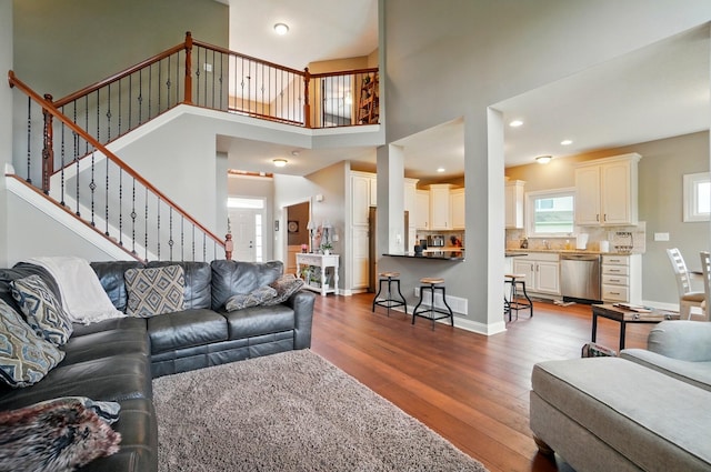 living room featuring baseboards, wood finished floors, stairway, and a towering ceiling