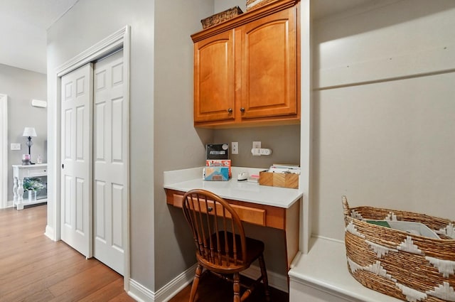 interior space featuring baseboards, light wood finished floors, and built in desk