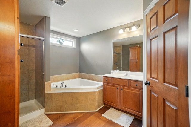 full bath featuring visible vents, a garden tub, vanity, wood finished floors, and a stall shower