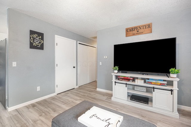 living area with a textured ceiling, baseboards, and light wood-type flooring