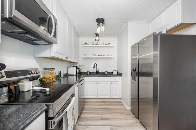 kitchen with a sink, appliances with stainless steel finishes, white cabinets, and light wood-style floors