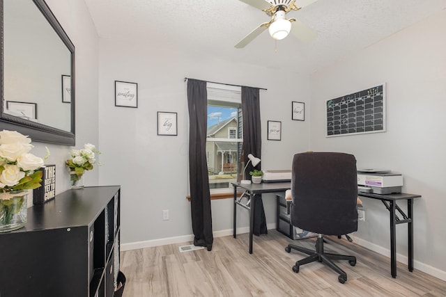 office featuring visible vents, baseboards, a textured ceiling, a ceiling fan, and light wood-style flooring