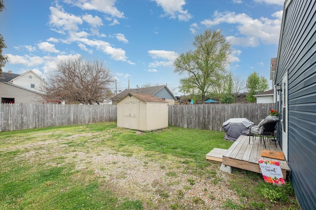 view of yard featuring a storage shed, a deck, an outdoor structure, and a fenced backyard