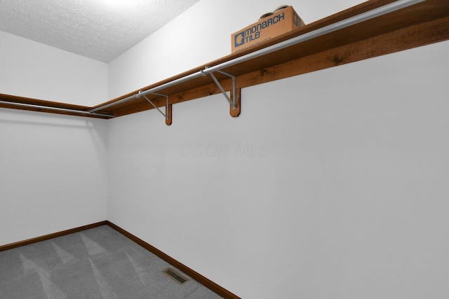 walk in closet with dark colored carpet and visible vents