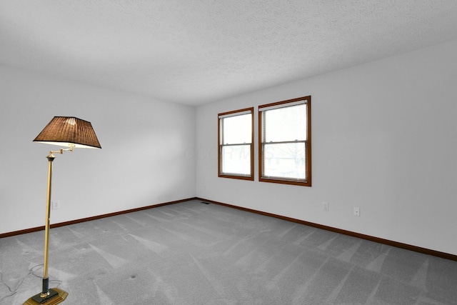 carpeted spare room featuring baseboards and a textured ceiling