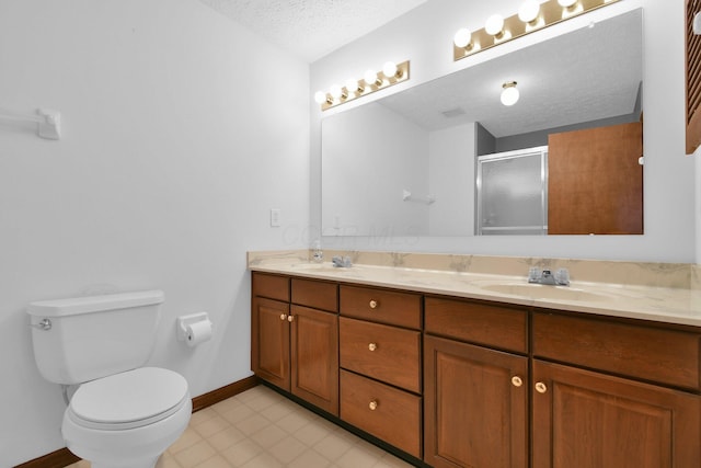 full bath featuring double vanity, toilet, a textured ceiling, a sink, and a stall shower