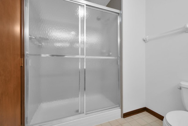 full bathroom with toilet, baseboards, and a shower stall