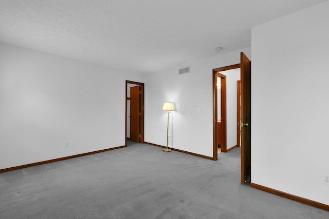 spare room with carpet flooring, baseboards, and visible vents