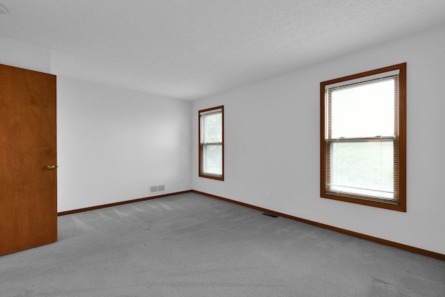 empty room with baseboards, carpet floors, and visible vents