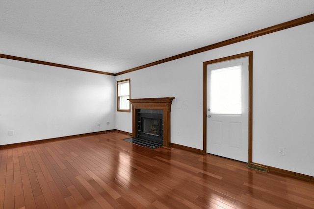 unfurnished living room with a fireplace with flush hearth, ornamental molding, wood finished floors, and visible vents