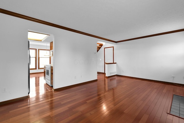 unfurnished living room with baseboards, wood-type flooring, crown molding, and visible vents