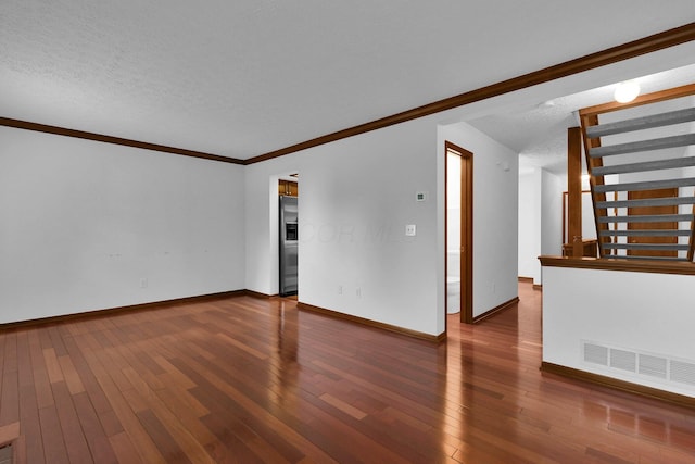 unfurnished room featuring a textured ceiling, visible vents, baseboards, wood-type flooring, and ornamental molding