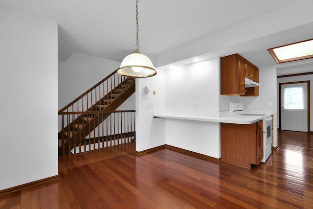 kitchen featuring brown cabinets, white electric range oven, baseboards, dark wood-type flooring, and under cabinet range hood