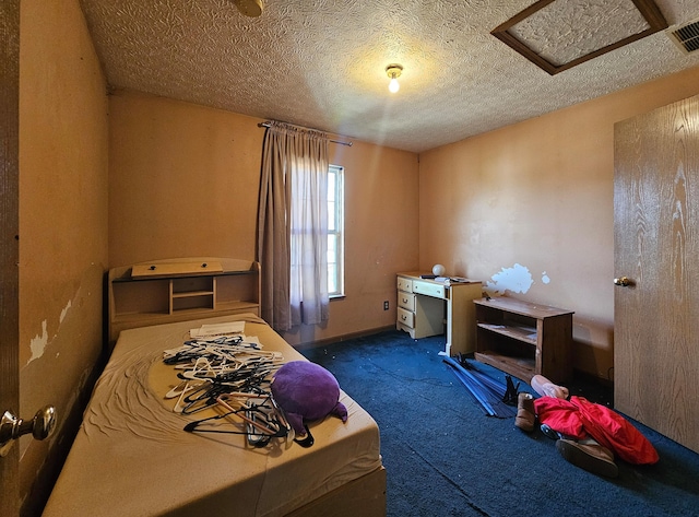 carpeted bedroom featuring visible vents, attic access, and a textured ceiling