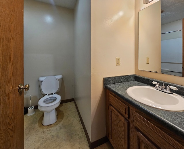 half bathroom with vanity, baseboards, and toilet