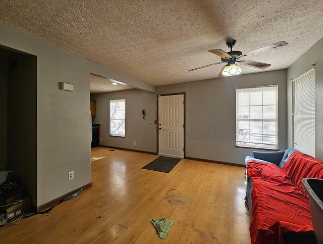 entryway featuring baseboards, a ceiling fan, light wood-type flooring, and a textured ceiling