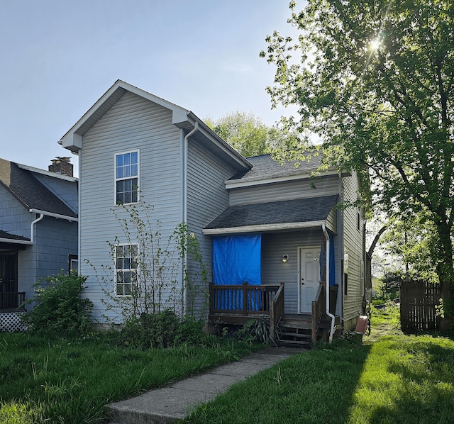 rear view of house with roof with shingles and covered porch