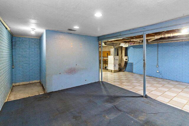 353 Clarendon Ave, Columbus, OH 43223 - unfinished basement featuring brick wall, tile patterned flooring, and heating unit