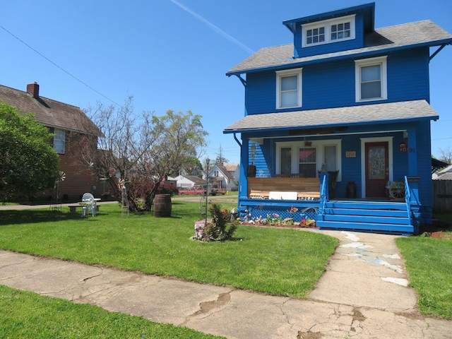 traditional style home featuring a porch, a shingled roof, and a front yard