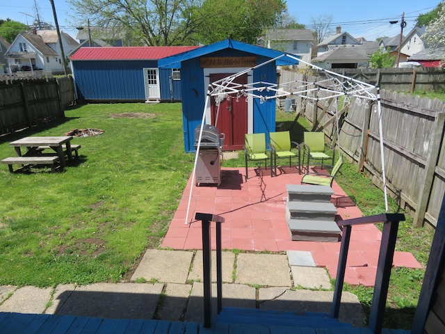 view of yard featuring a fenced backyard, a shed, an outbuilding, and a residential view