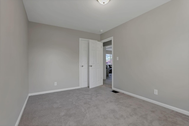 unfurnished bedroom featuring baseboards, visible vents, carpet, and a closet