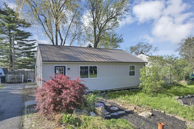 view of front of property featuring fence, metal roof, and aphalt driveway