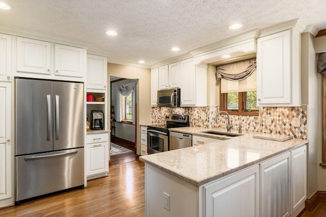 12385 Woodsfield Cir E, Pickerington, OH 43147 - kitchen with crown molding, wood finished floors, light stone counters, a sink, and appliances with stainless steel finishes