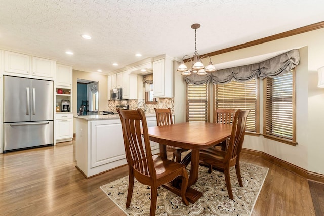 12385 Woodsfield Cir E, Pickerington, OH 43147 - dining room featuring a textured ceiling, crown molding, wood finished floors, baseboards, and an inviting chandelier