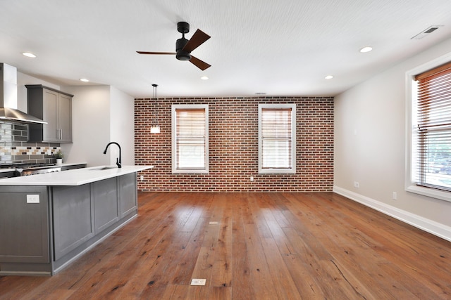 1012 Ewing Aly, Columbus, OH 43201 - kitchen featuring brick wall, ceiling fan, gray cabinets, wall chimney exhaust hood, and a sink