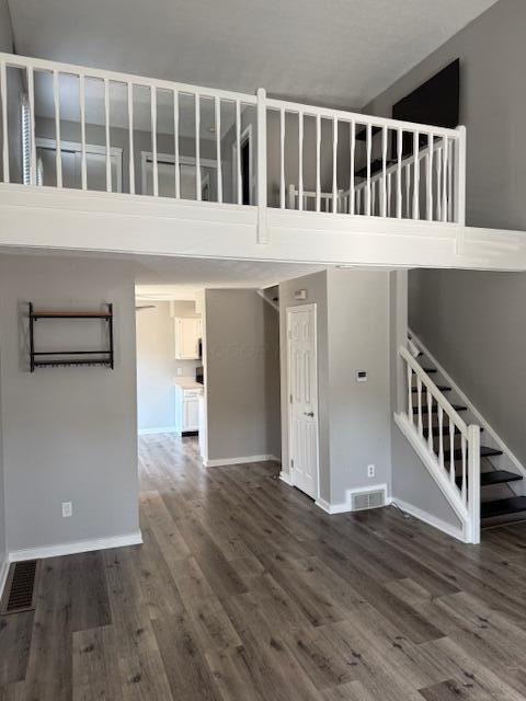 302 Saint Andrews Dr Unit 302, Dublin, OH 43017 - unfurnished living room with dark wood-type flooring, a high ceiling, and stairs
