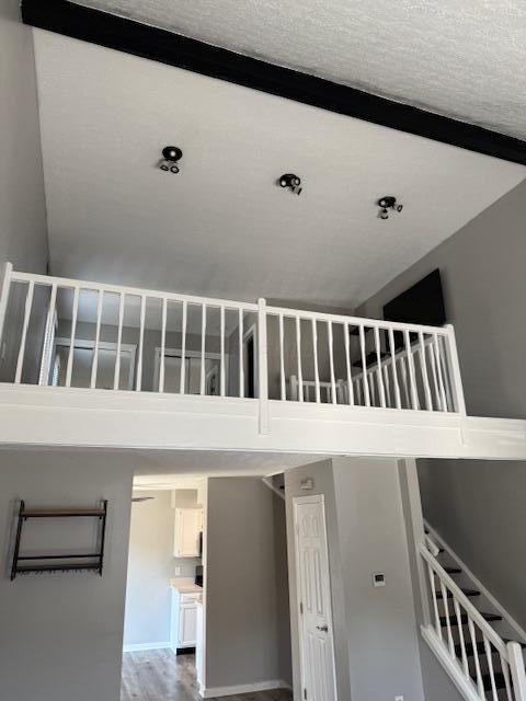 302 Saint Andrews Dr Unit 302, Dublin, OH 43017 - stairs featuring wood finished floors, a towering ceiling, and a textured ceiling