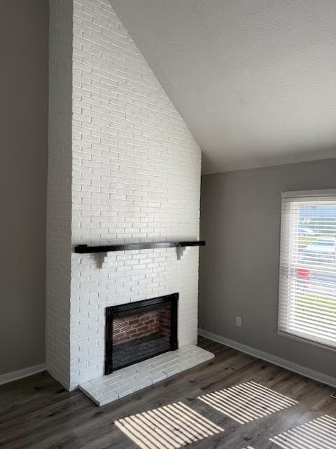 302 Saint Andrews Dr Unit 302, Dublin, OH 43017 - unfurnished living room with vaulted ceiling, a brick fireplace, and wood finished floors