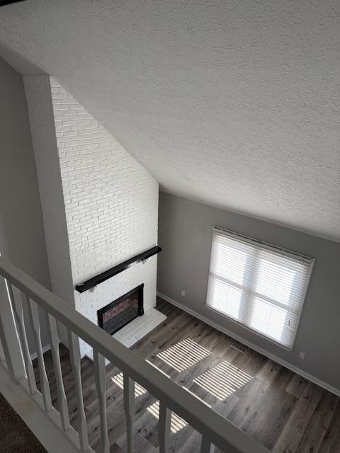 302 Saint Andrews Dr Unit 302, Dublin, OH 43017 - staircase with a fireplace, a textured ceiling, lofted ceiling, and wood finished floors
