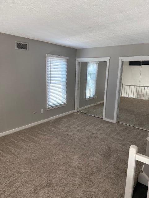 302 Saint Andrews Dr Unit 302, Dublin, OH 43017 - unfurnished bedroom featuring multiple closets, carpet floors, and a textured ceiling