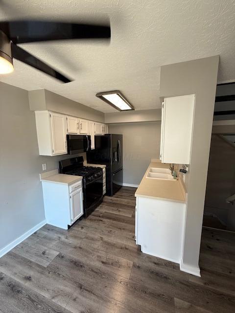 302 Saint Andrews Dr Unit 302, Dublin, OH 43017 - kitchen with black appliances, dark wood-style floors, light countertops, white cabinetry, and a textured ceiling