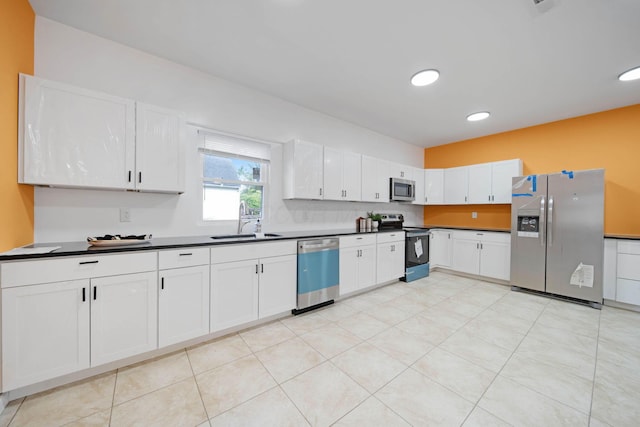 kitchen featuring stainless steel appliances, a sink, dark countertops, white cabinetry, and recessed lighting