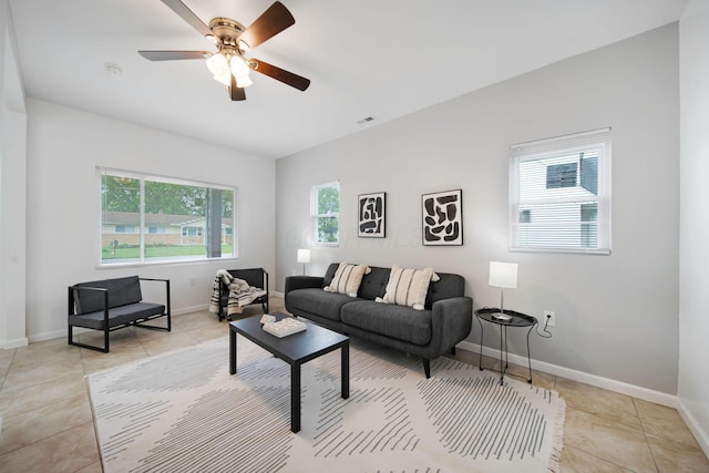 living room featuring light tile patterned floors, ceiling fan, and baseboards
