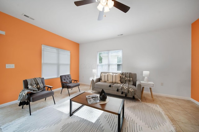 living room with light tile patterned floors, ceiling fan, and baseboards