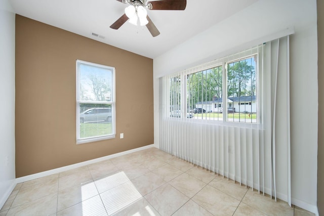 tiled spare room featuring ceiling fan and baseboards