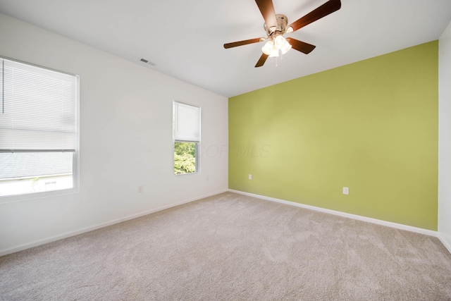 unfurnished room with plenty of natural light, light carpet, baseboards, and a ceiling fan