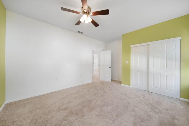 unfurnished bedroom with carpet flooring, a closet, baseboards, and a ceiling fan