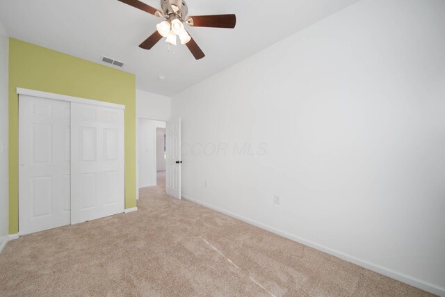 unfurnished bedroom featuring light colored carpet, baseboards, a closet, and a ceiling fan