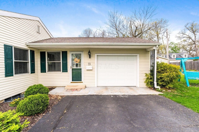 ranch-style house featuring an attached garage, fence, a shingled roof, and aphalt driveway